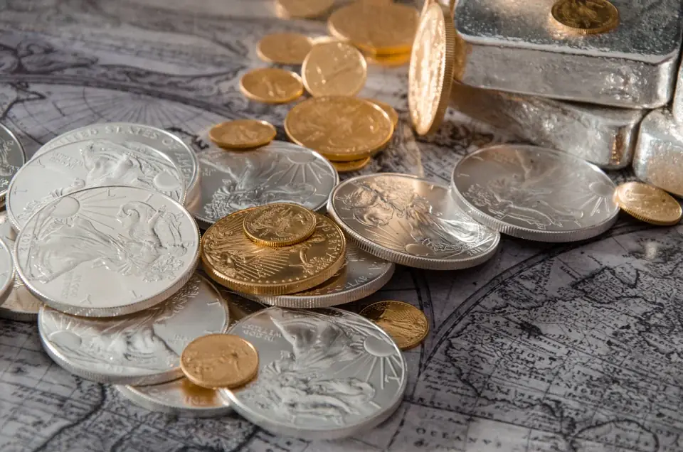 Silver Eagles, small gold coins and poured silver bars spread over an old printed map
