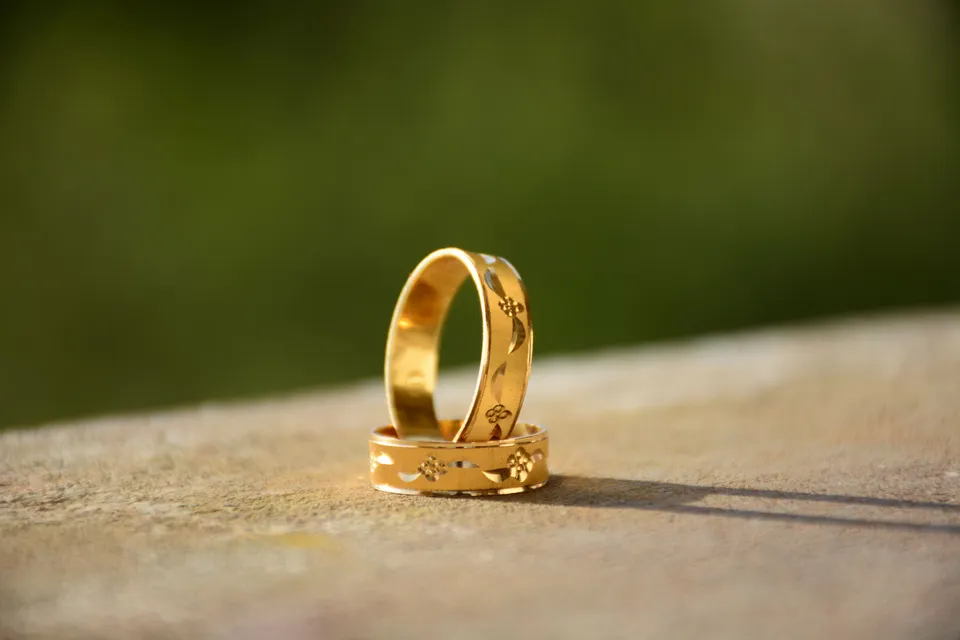 Two engraved gold rings resting on a sunlit stone ledge